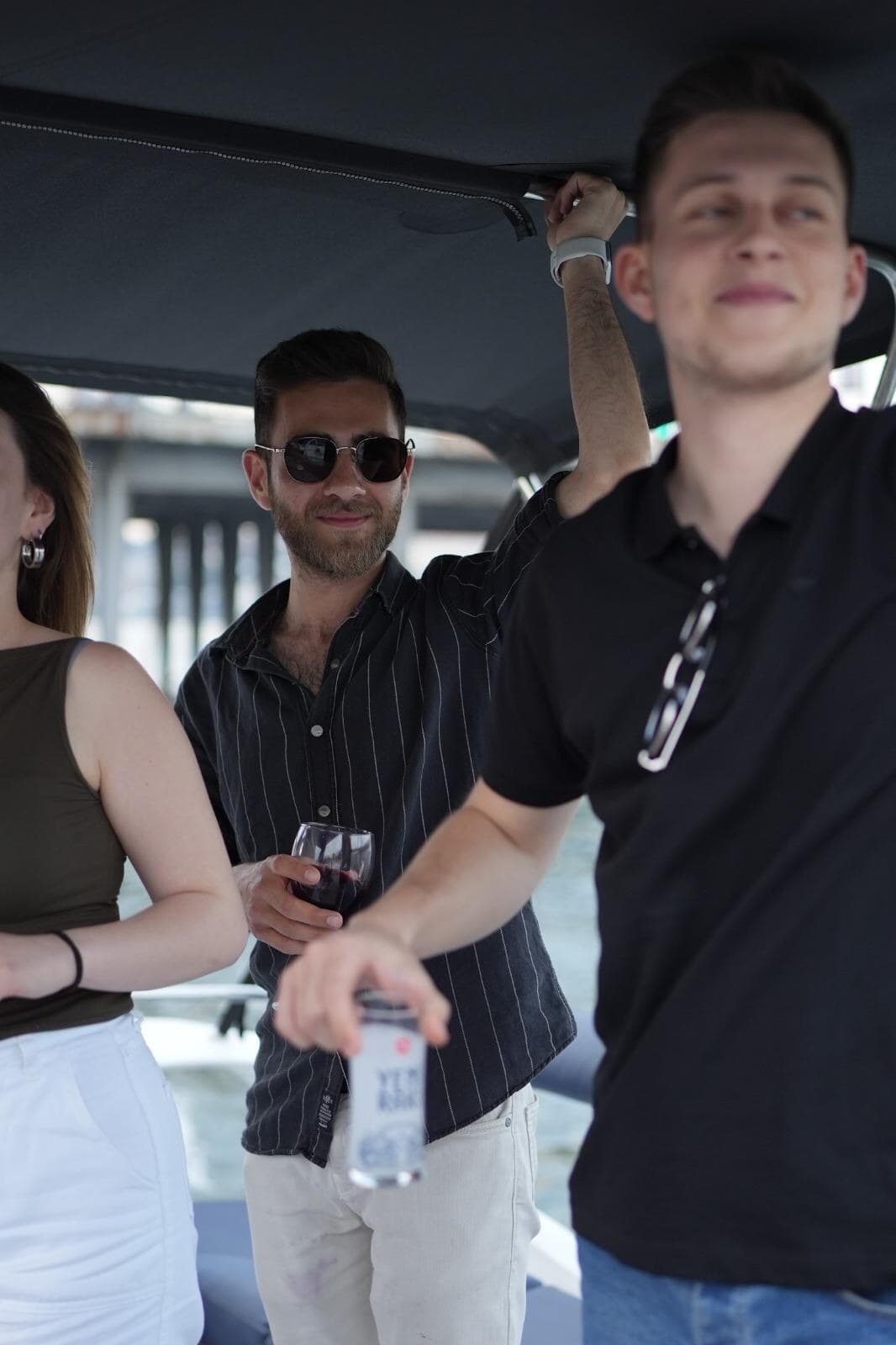 Guests under the deck canopy with drinks as the boat passes a Bosphorus bridge
